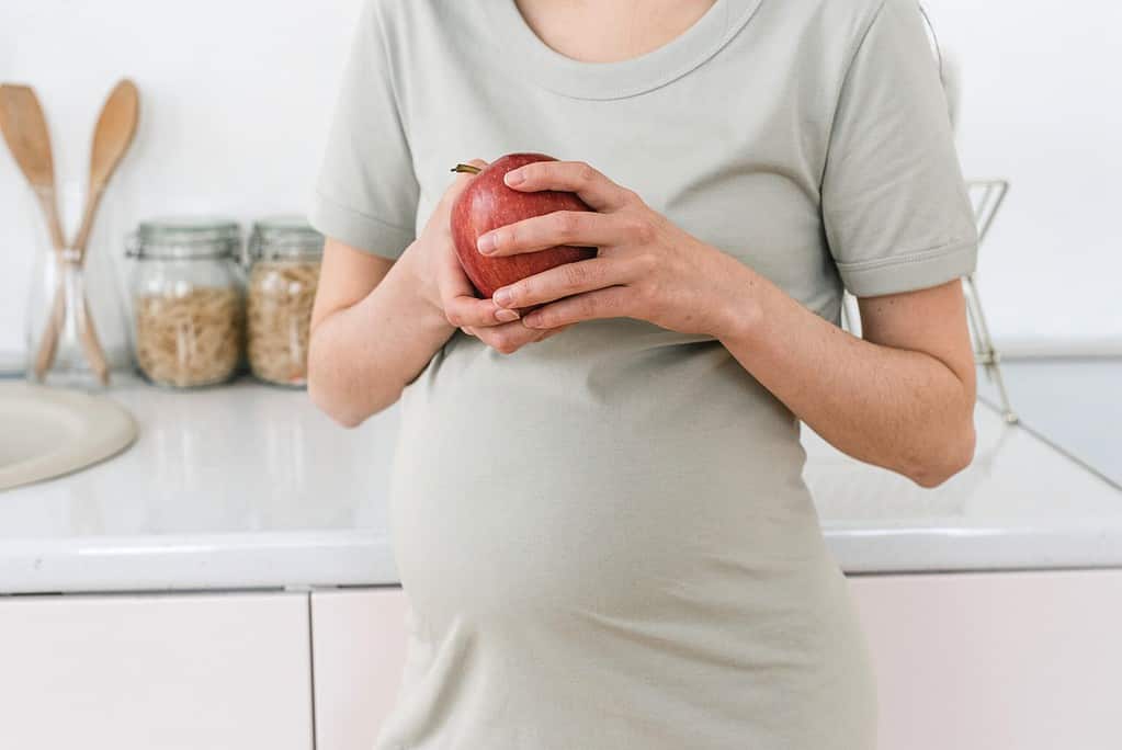 Donna incinta in cucina con una mela fra le mani